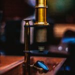 Close-up of an antique brass microscope with a blurred background in an indoor setting.